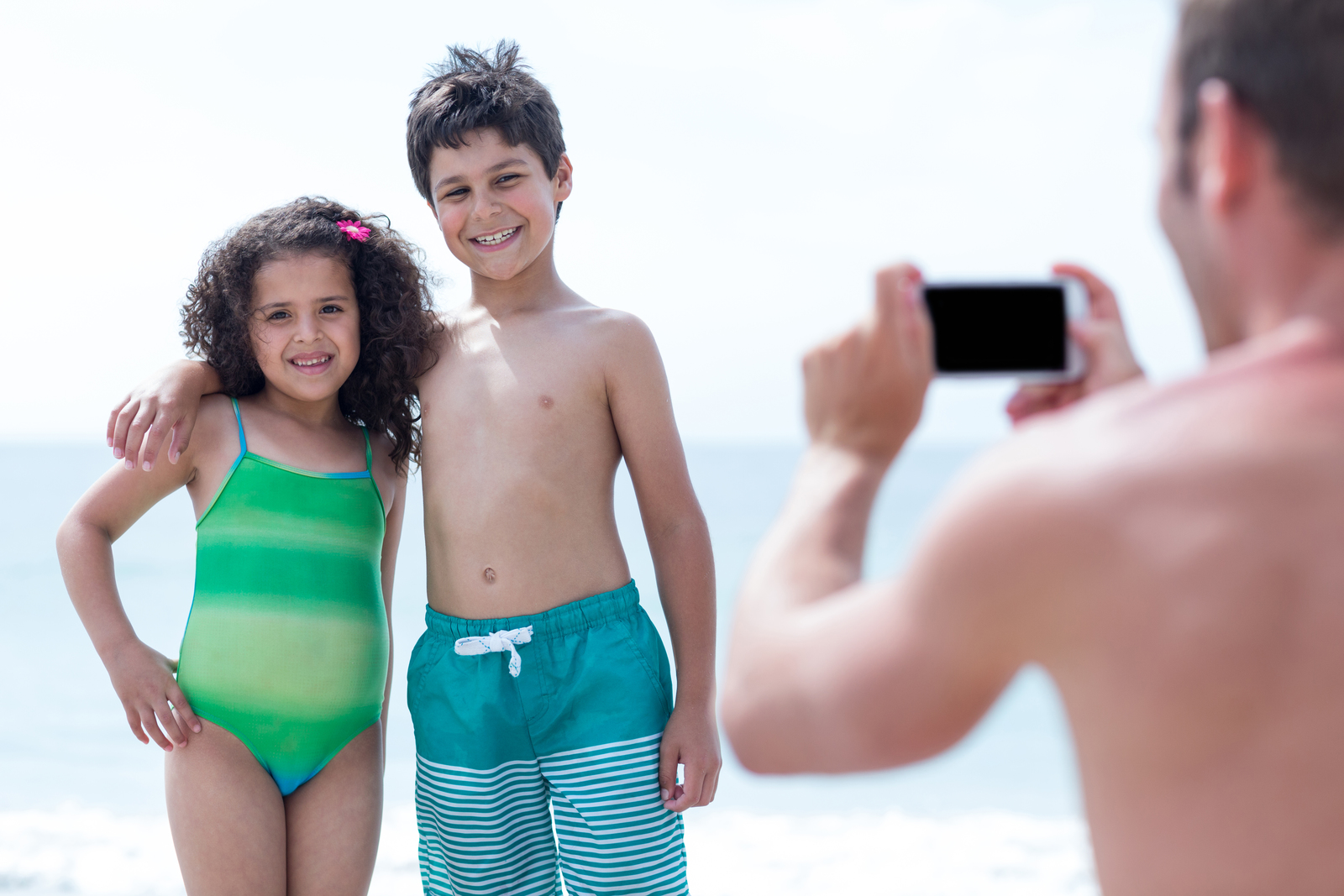 29170940_father-photographing-smiling-children-at-beach