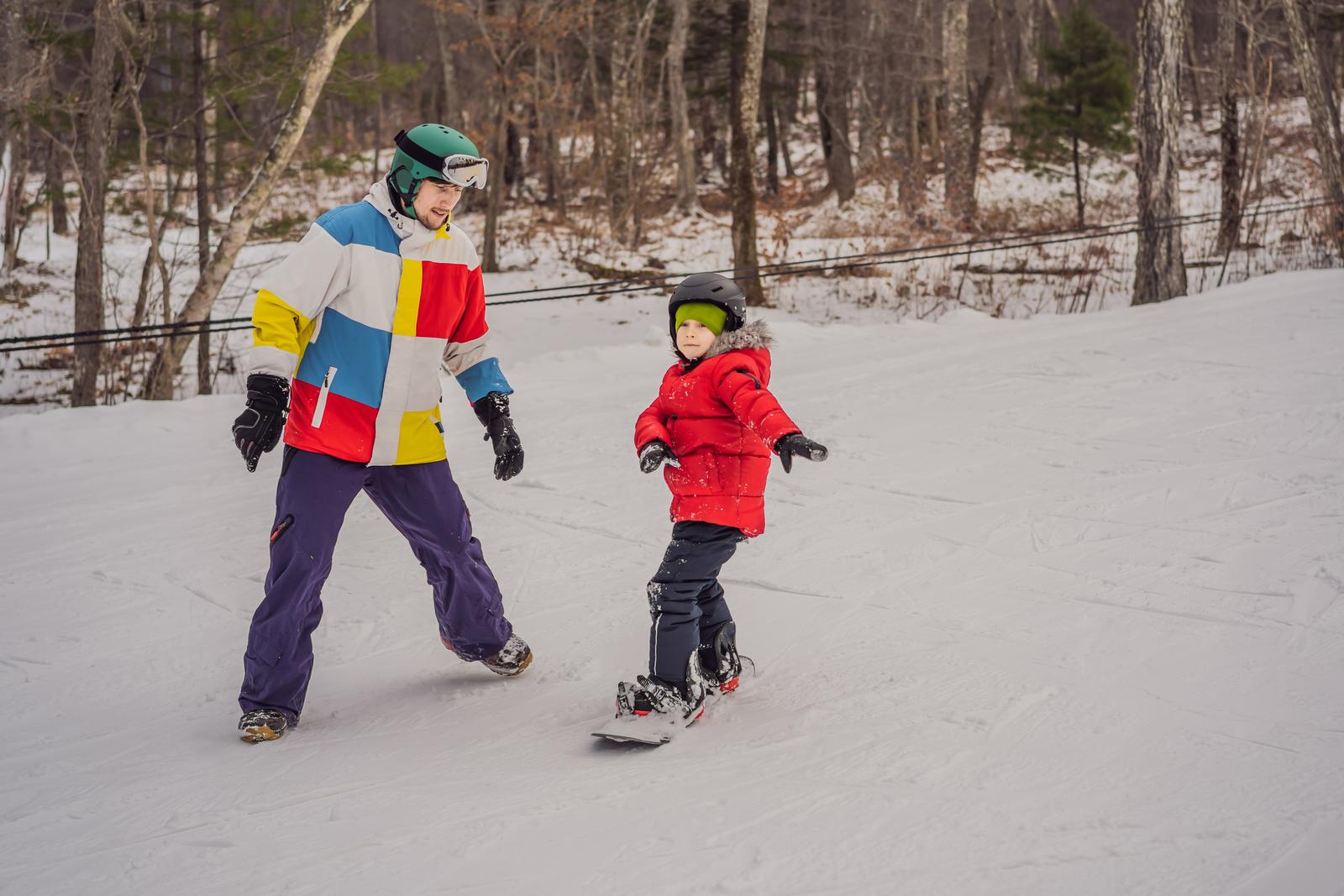 Snowboard instructor teaches a boy to snowboarding. Activities for children in winter. Children's winter sport. Lifestyle.